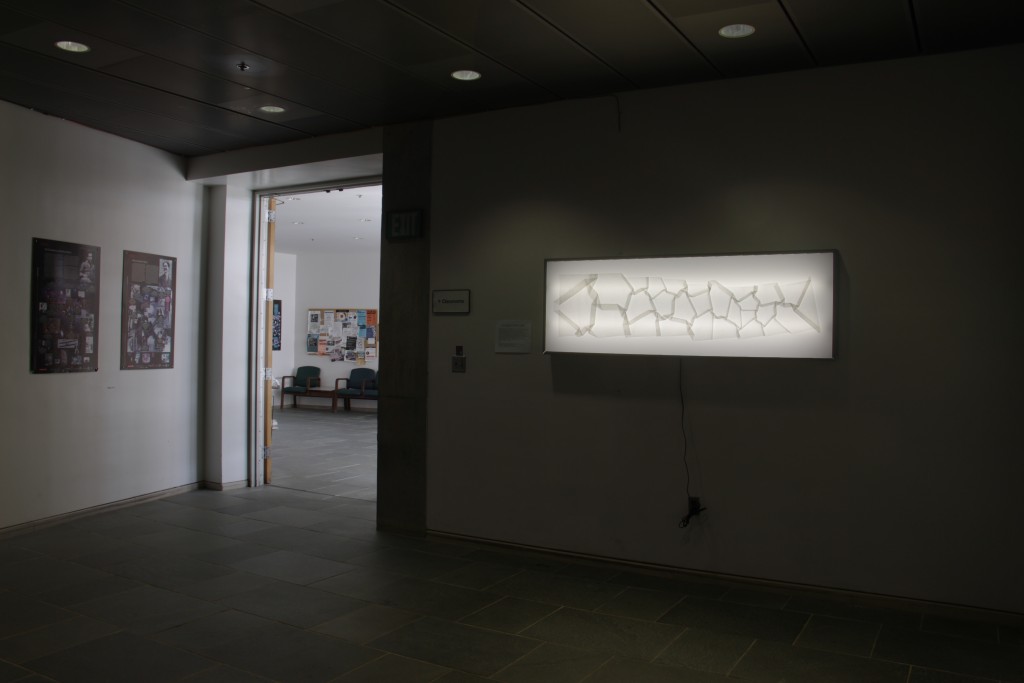 The Origami Cosmic Web is laid out on a light box that is attached from a gallery wall. 