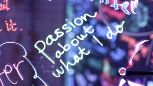An extreme close up of "Passion about what I do" written on an acrylic panel in neon marker.