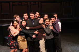 A group of students that represent the Barnstormers, stand center stage, huddled tightly together. 