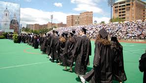 Students line-up on an outdoor field wearing their cap and gowns.