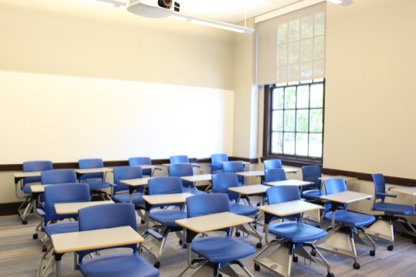 Empty Krieger 302 classroom showing individual desk and chair seating.