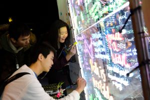 A photo of students drawing on an interactive, LED powered art installation. 