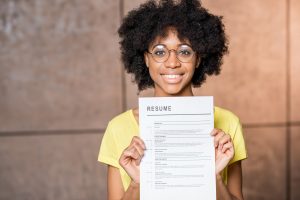 Portrait of a young african woman holding resume document indoors