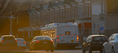 A bus driving with the Baltimore skyline in the background.