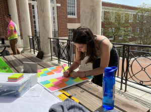Young woman writes on sticky notes stuck on pasteboard on a sunny day.