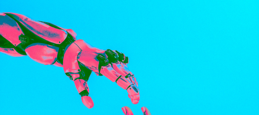 Full color image of a neon pink robot hand reaching across a bright teal background toward a neon pink human hand. Photo by Cash Macanaya on Unsplash.