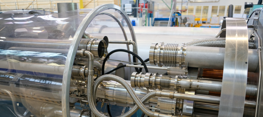 A full-color image of a component of the Large Hadron Collider in Switzerland. Image features various steel and chrome components encapsulated in a clear glass casing. Photo by Brandon Style on Unsplash.