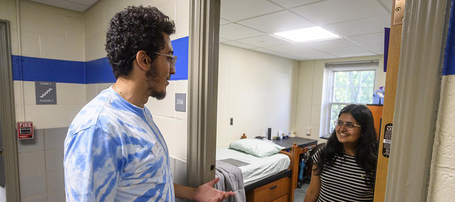 A student speaks to an RA while standing in the doorway of her room