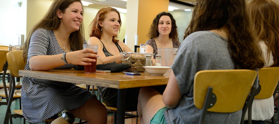 Students talking at table in dining hall.