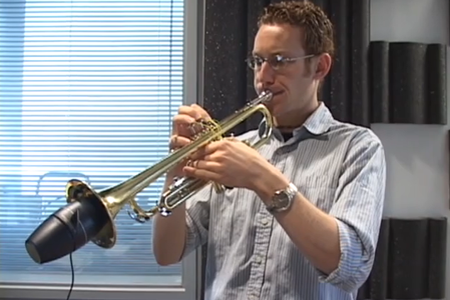 A man playing a trumpet in a casual, unknown space.