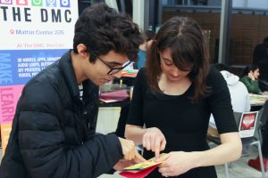 Two students huddle together looking at a handmade card.