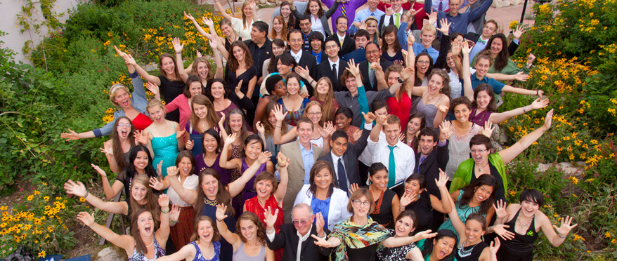 A group of students look overhead to smile and wave enthusiastically.