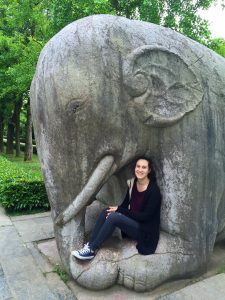 Christina Meyer sits at the foot of an elephant statue.