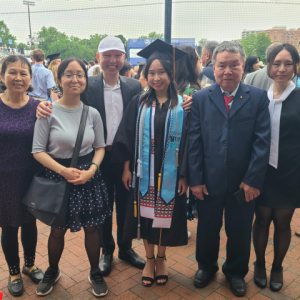 Family photo of Hopkins student Sandy Wong at commencement. She is wearing her graduation robe and cap, smiling with her family on both sides.