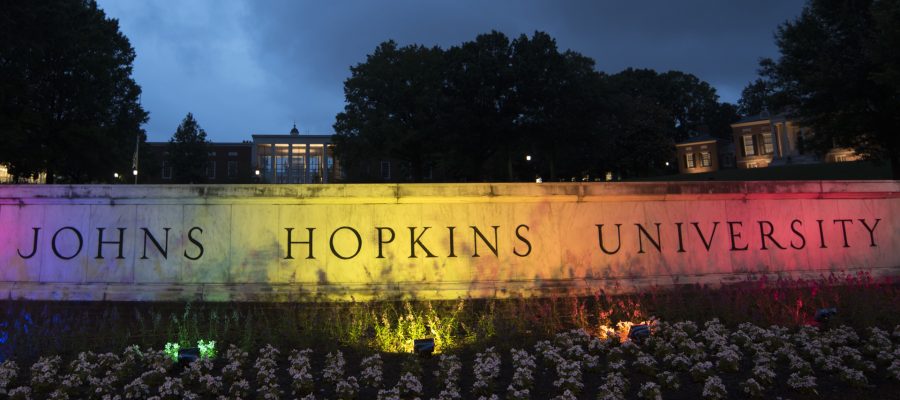The JHU sign is lit up in the colors of the rainbow flag