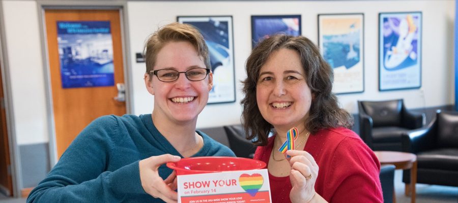 two smiling people hold up show your love ribbons