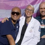 three people in front of the trans flag