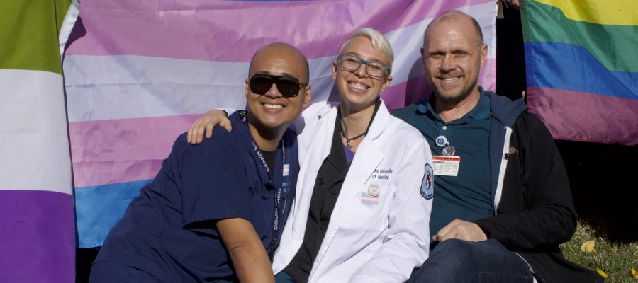 three people in front of the trans flag