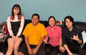 Carol Lu and her family sit on a sofa in her residence hall