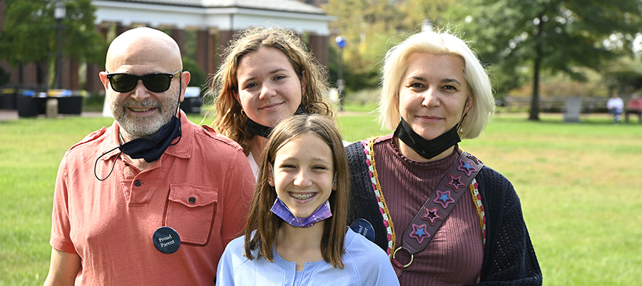 Parents smile for a posed photo with their two daughters outdoors on JHU's campus