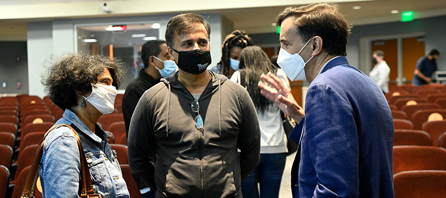 Two parents speak with President Daniels while wearing face masks