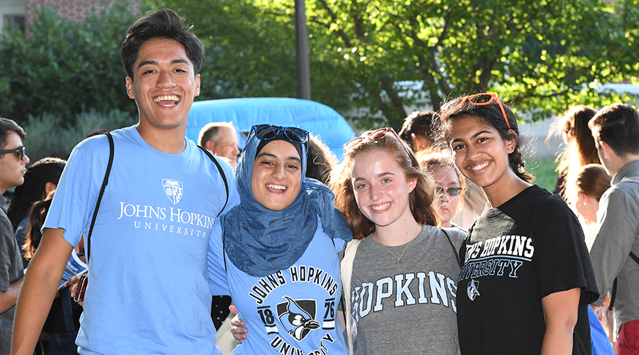 Four Hopkins students smile at an outdoor event