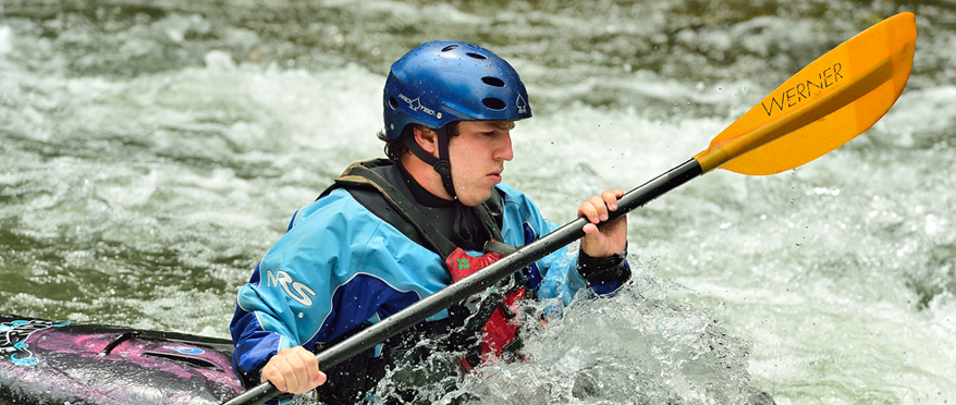 A student focused on maneuvering his kayak in the water.