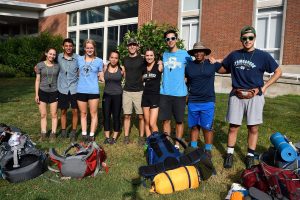 A group of nine first-year students pose for a photo on campus for Outdoor Pursuits