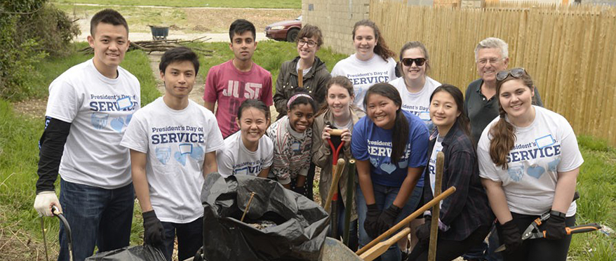 picture of president's day of service volunteers who are cleaning up an outdoor green space