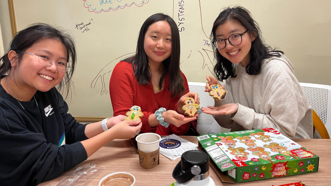 Three Baltimore First members smiling in the CSC Conference Room holding decorated cookies.