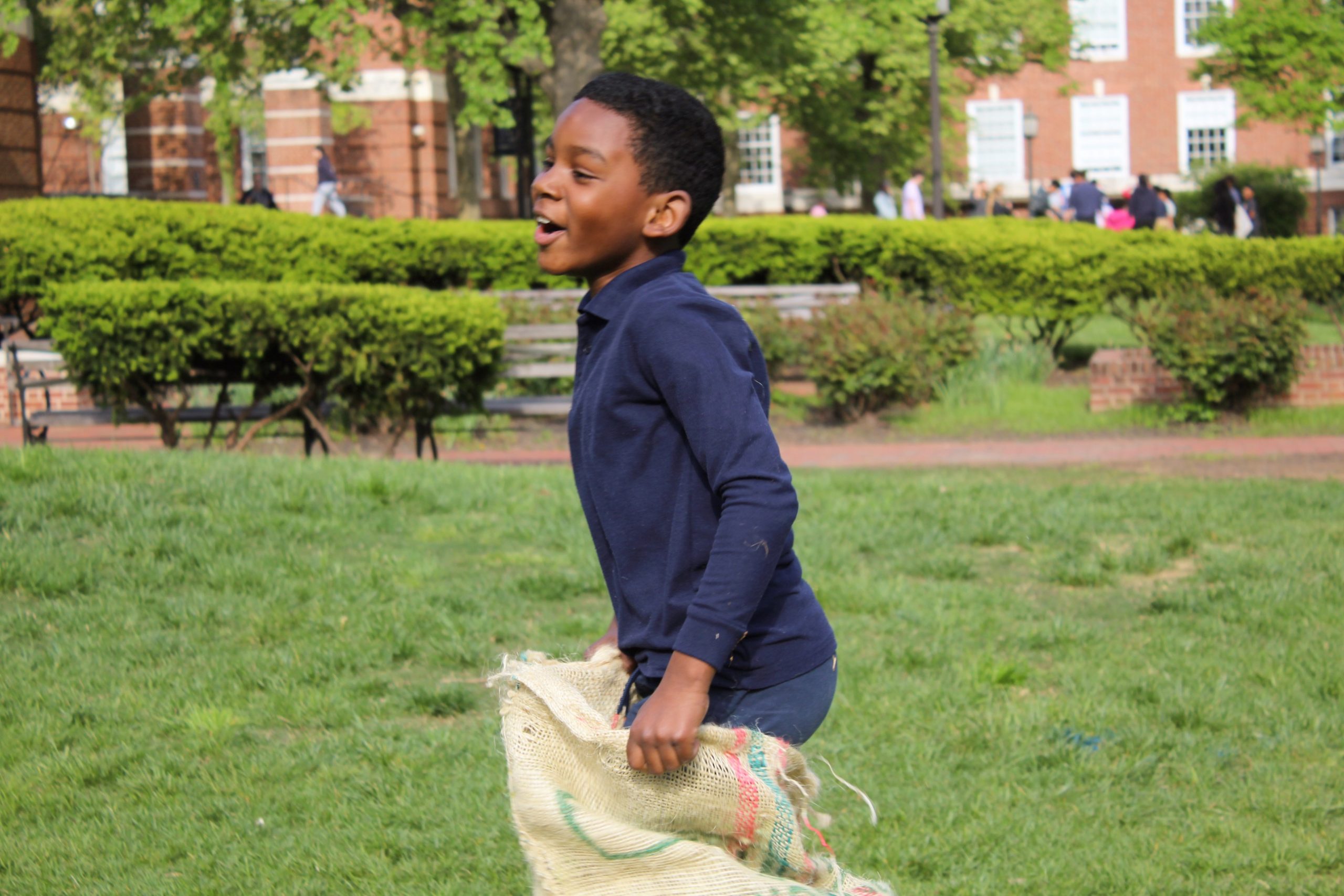 Candid shot of a tutee smiling while sack racing at the 2023 field day