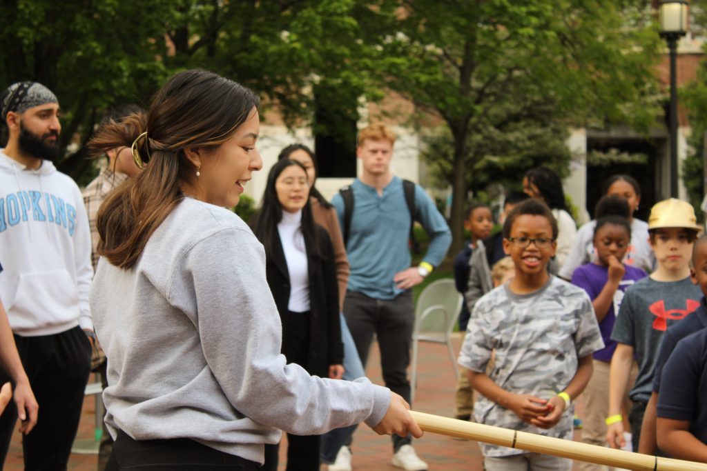 Tutor holding the limbo stick at the 2023 field day
