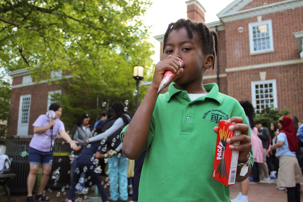A tutee eating an icee while holding pocky sticks at the 2023 field day.