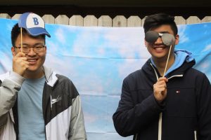 Two students smiling holding up sunglasses