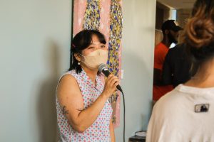 Clarissa Chen speaking into a microphone. She is wearing a mask.