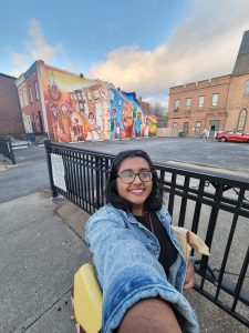 Diksha smiling outside of a mural