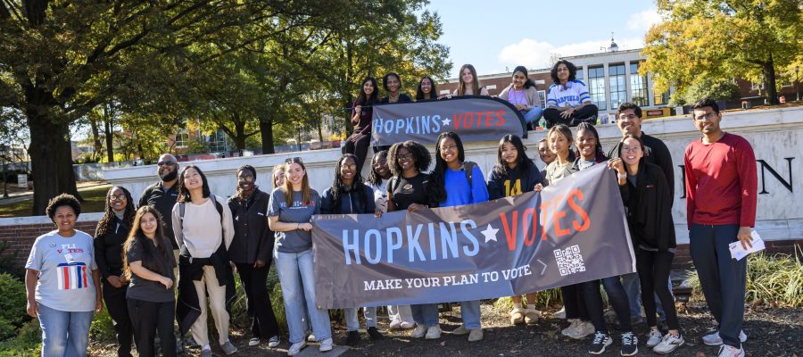 Students, faculty, and staff gather around election day banner